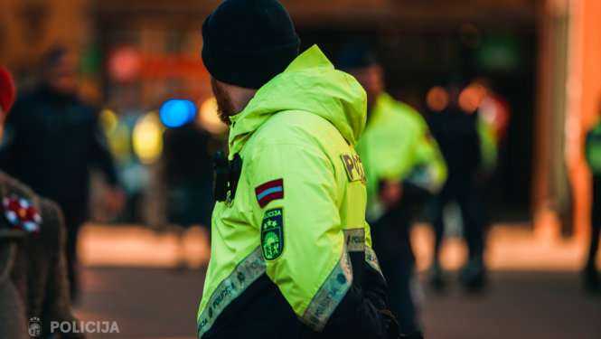 policists stāv sabiedriskā vietā aizgriezis seju, formā