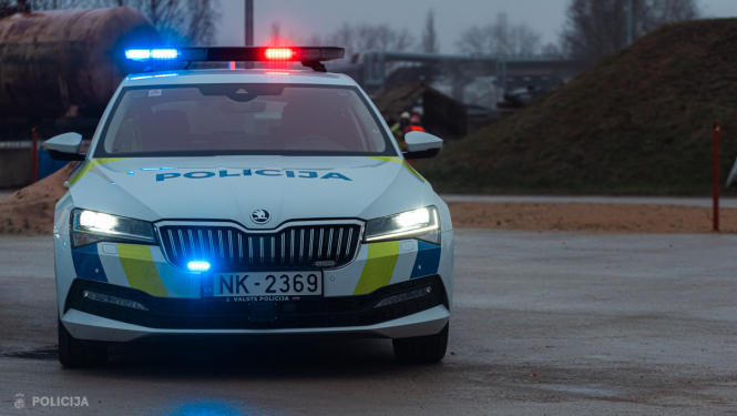 Valsts policijas automašīna ar ieslēgtām bākugunīm ceļa malā