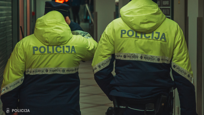 Divi policisti formas tērpos ar mugurām pret skatītāju