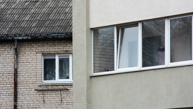 Daudzdzīvokļu mājas logi, fonā redzama vēl viena ēka