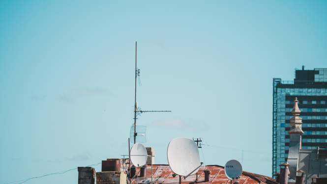 Ēkas jumts ar antenām un satelīta šķīvjiem pilsētvidē
