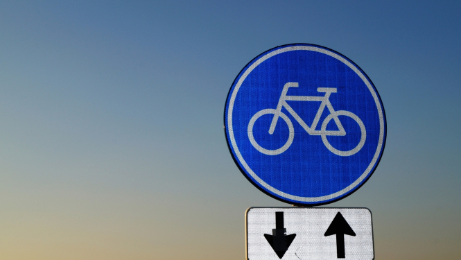 Uz debesu fona redzama ceļazīme "Velosipēdu ceļš" ar darbības virzienu papildzīmi 