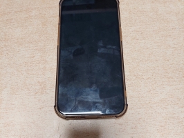 Apple mobilais telefons caurspīdīgā vāciņā fotografēts no priekšpuses, ar ieslēgtu ekrānu un no aizmugures uz gaišas koka virsmas