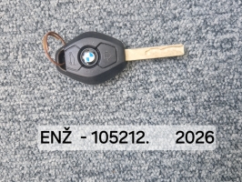 BMW automašīnas atslēga ar melnu korpusu un metāla atslēgas asmeni uz pelēkas virsmas.