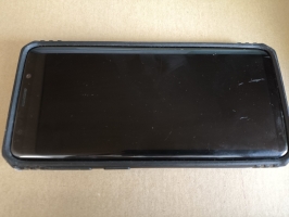 Melns mobilais telefons Samsung ar zilu silikona maciņu.