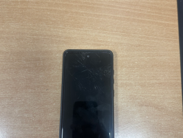 Mobilais telefons "Samsung" ar melnas krāsas vāciņu, uz kura sāniem uzraksts "Rhinoshield”.