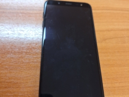 Mobilais telefons "Samsung" melnā krāsā ar uzlīmēm uz aizmugures vāciņa.