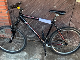 Melns velosipēds "Dema". Uz velosipēda rāmja augšējās daļas ir uzraksts "Pegas", bet uz stūres iznesuma – dzeltena lenta.
