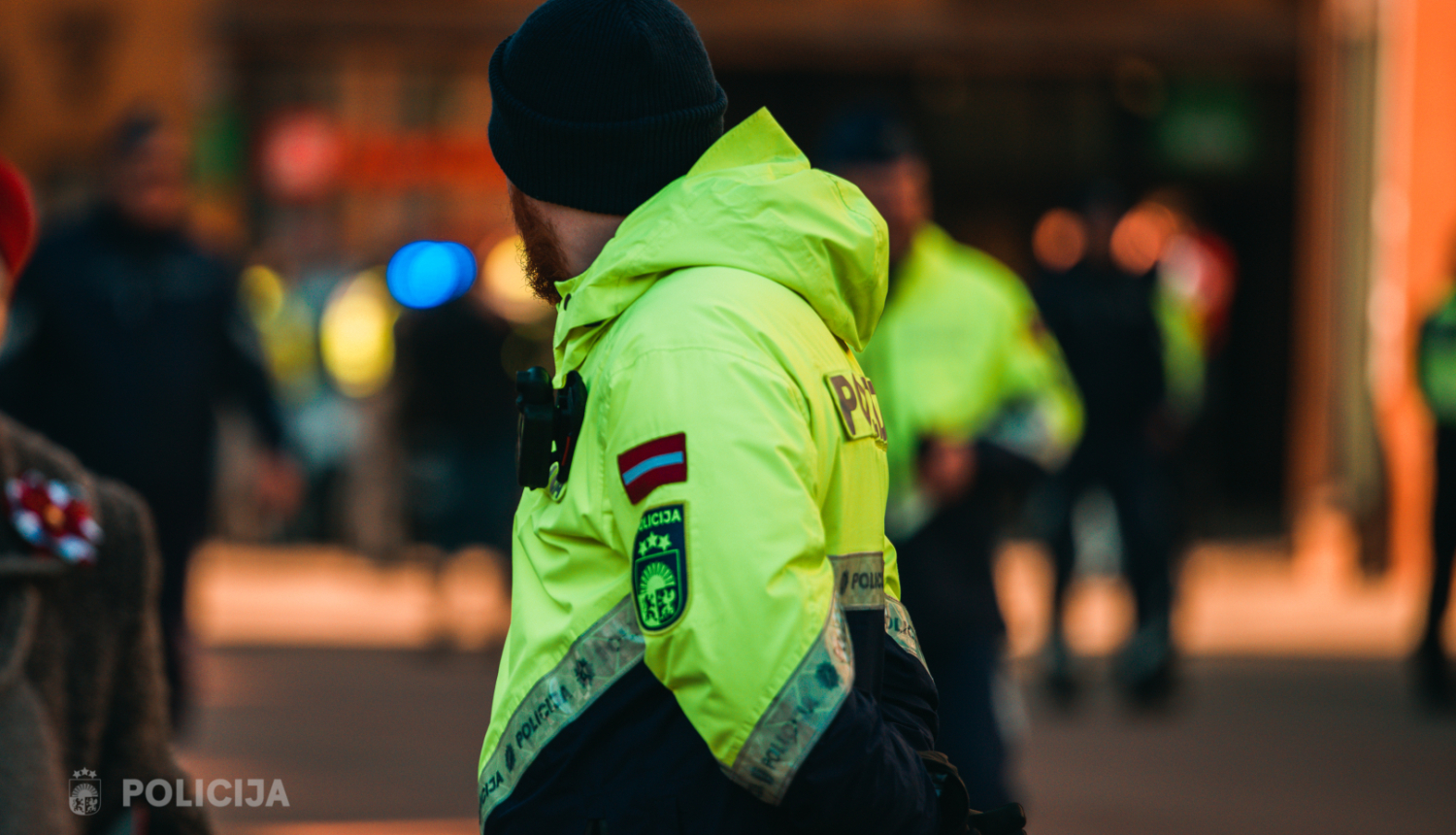policists stāv sabiedriskā vietā aizgriezis seju, formā