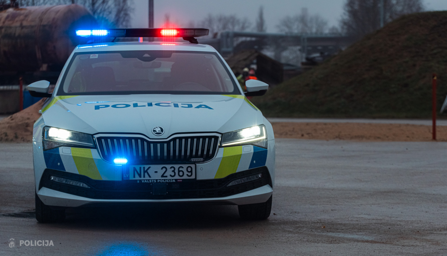 Valsts policijas automašīna ar ieslēgtām bākugunīm ceļa malā