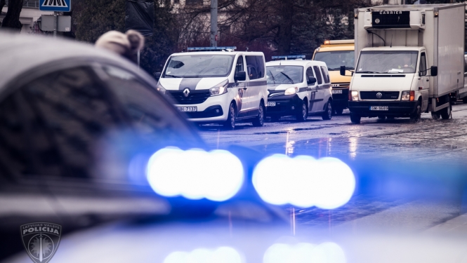 foto ar satiksmi un policijas auto ar ieslēgtām zilām bākugunīm