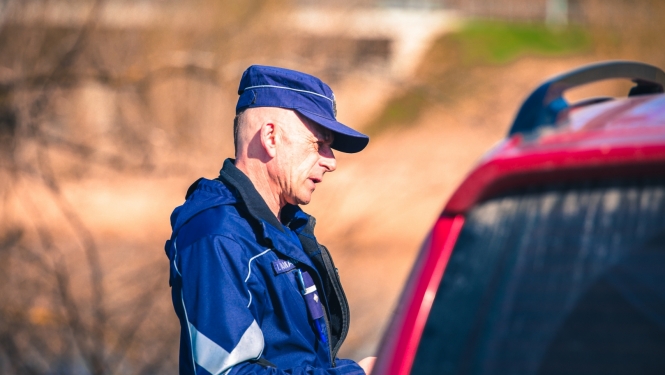 Valsts policijas darbinieks pie automašīnas