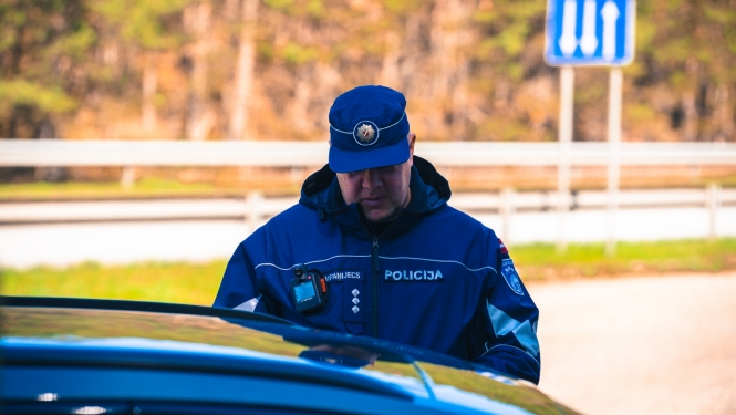 Valsts policijas darbinieks pie automašīnas