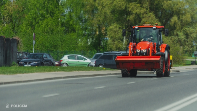 Sarkans traktors pārvietojas pa ielu