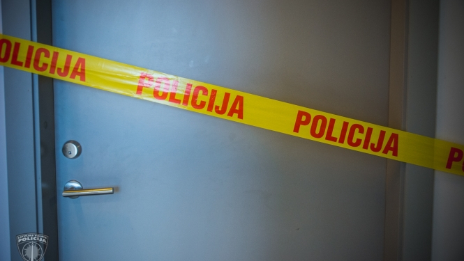 Aizvērtas durvis, kurām priekšā pa diagonāli novilkta dzeltena lenta, uz tās ar sarkaniem burtiem uzrakstīts POLICIJA