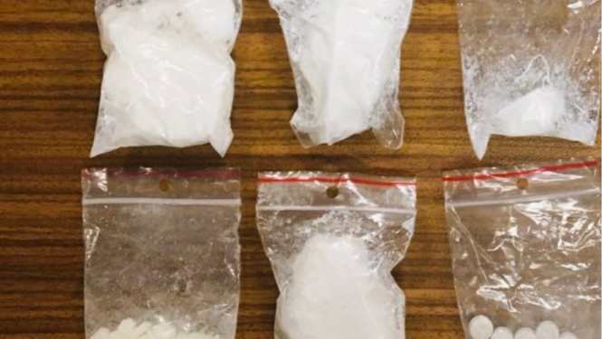 Seši caurspīdīgas plastmasas maisiņi, kuros ir baltas krāsas pulverveida viela un vienā vairākas baltas krāsas tabletes