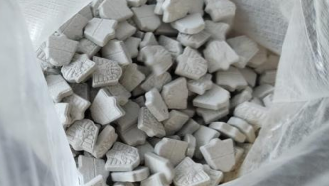 Atvērts polietilēna maiss un tajā redzamas daudz pelēkas MDMA tabletes 
