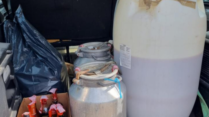 Muca un kannas, un kaste ar pudelēm, kurās atrodas nelegālais alkohols