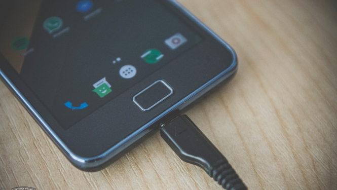 Mobilais tālrunis, kas pievienots pie lādētāja