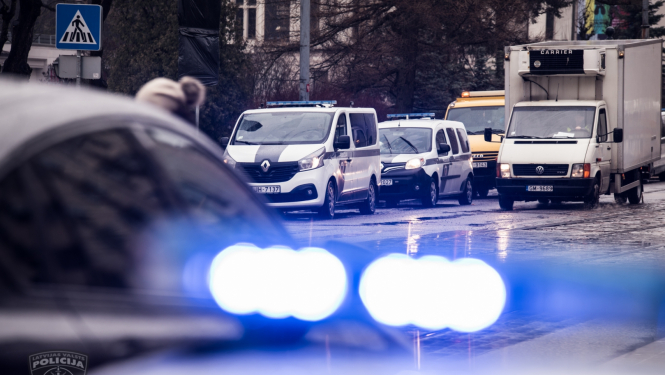 foto ar satiksmi un policijas auto ar ieslēgtām zilām bākugunīm