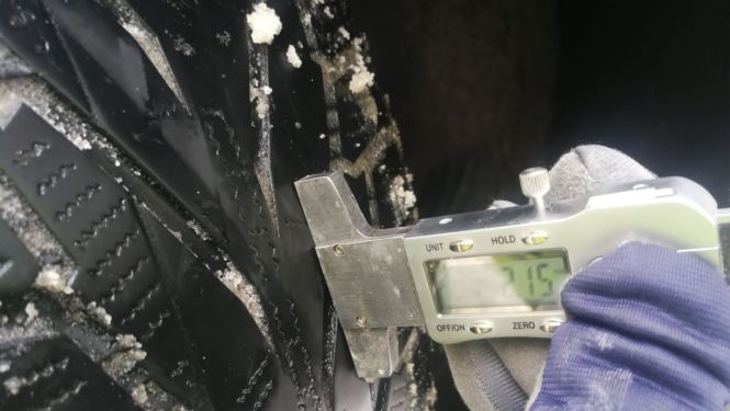 Mašīnas riepas protektora dziļuma pa®baude, kurā uzrādās 2,15