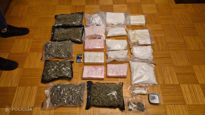 Uz grīdas izkārtoti policijas izņemti narkotisko vielu iepakojumi, vairāki vakuuma maisi ar augu izcelsmes vielu, plastmasas maisiņi un iepakojumi ar baltu pulverveida vielu