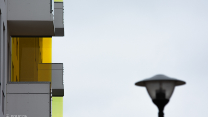 Daudzdzīvokļu mājas balkoni attēla kreisajā pusē un labajā pusē laterna 