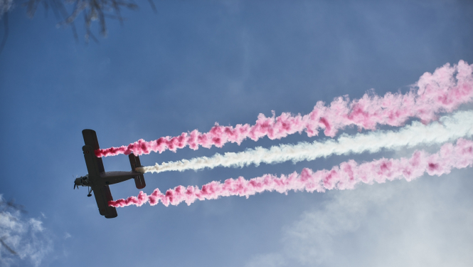 Lidmašīna debesīs veido krāsainu sarkanbaltsarkanu dūmu līnijas debesīs