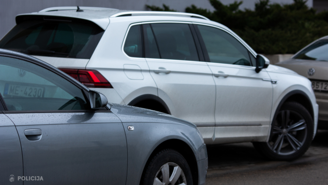 Uz mitra ceļa novietotas vairākas vieglās automašīnas, priekšplānā redzams pelēks auto, bet fonā balts auto