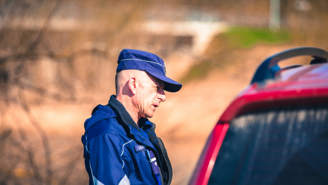 Valsts policijas darbinieks pie automašīnas
