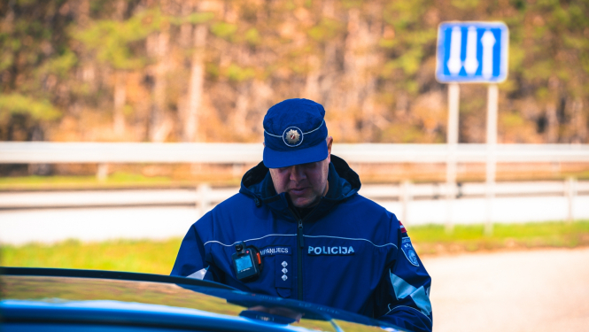 Valsts policijas darbinieks pie automašīnas