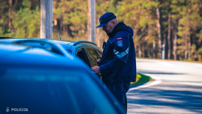 Valsts policijas darbinieks pie automašīnas