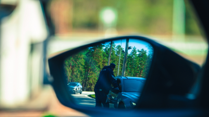Valsts policijas darbinieks pie automašīnas
