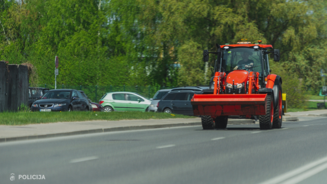 Sarkans traktors pārvietojas pa ielu