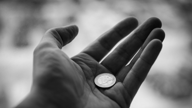 Melnbalts attēls, kurā redzams viens eiro atvērtā plaukstā