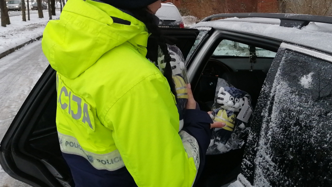 Policists, kas sniedz mašīnas virzienā mantiņu