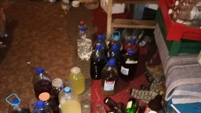 Uz grīdas redzamas dažāda tilpuma pudeles ar dažādas krāsas nelikumīgu alkoholu