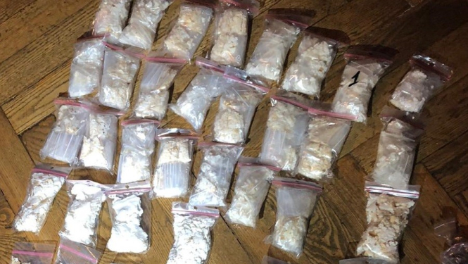 Uz grīdas vairāki caurspīdīga polietilēna maisiņi, kuros atrodas narkotiskās vielas