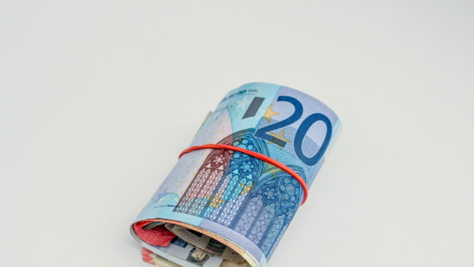 20 eiro banknote sarullēta kopā ar citu nominālu banknotēm un aplikta apkārt sarkana gumija