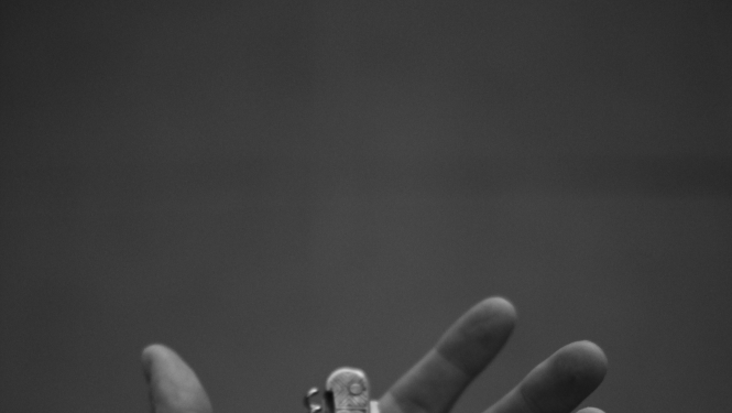 Cilvēka plaukstā ievietots saliekamais nazis. Plauksta atvērta, pavērsta uz augšu. Melnbaltā bilde.