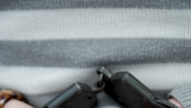 Sievietes rokas uz muguras saslēgtas rokudzelžos