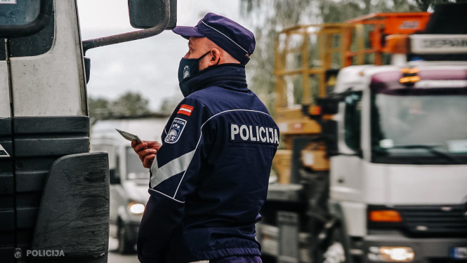 Valsts policijas darbinieks pie kravas mašīnas stāv