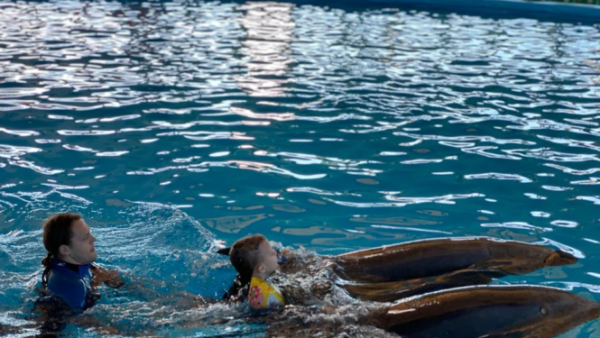 Policista dēls Rūdolfs peld kopā ar diviem delfīniem