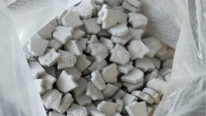 Atvērts polietilēna maiss un tajā redzamas daudz pelēkas MDMA tabletes 