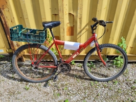 sarkans velosipēds ar zaļu augļu kasti