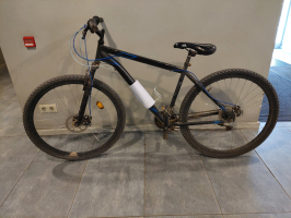 melns velosipēds atstutēts pret gaišu sienu