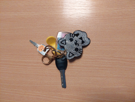 atslēgu saisķis ar kaķa formas piekariņu novietots uz koka imitācijas virsmas