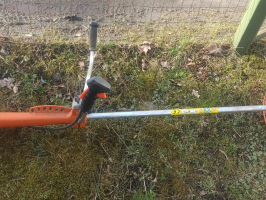 trimmeris ar oranžā krāsā novietots uz zāles seguma