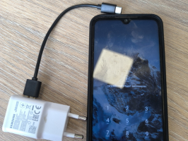 mobilais telefons redmi ar lādētāju un vadu