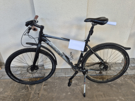 melns velosipēds atstutēts pret gaišu sienu